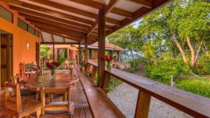 um alpendre de uma casa com uma mesa de madeira e cadeiras em Casa jessica em Hone Creek