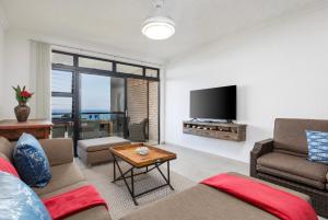 a living room with a couch and a flat screen tv at Summer Rocks 10 in Uvongo Beach
