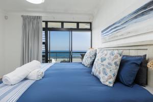 a bedroom with a blue bed with a view of the ocean at Summer Rocks 10 in Uvongo Beach +20 photos