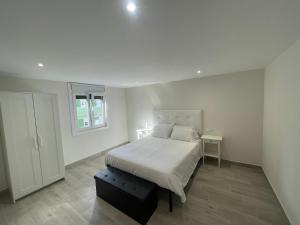 a white bedroom with a bed and a window at Camiño da Camposa in Muxia