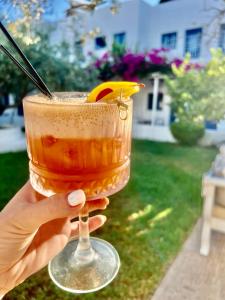 a hand holding a drink with a lemon slice in it at Lindos Athena in Lindos