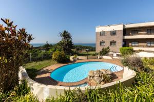a swimming pool in front of a building at Summer Rocks 10 in Uvongo Beach