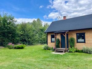 a house with a grass yard next to a house at Domek pod Dębem in Szymonowo