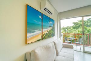 sala de estar con sofá y una foto de la playa en Flat Ile de Pipa Premium Positano by QAVI, en Pipa
