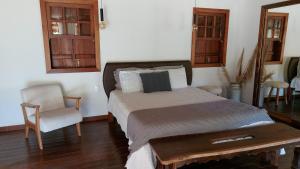 a bedroom with a large bed and a chair at Caminhos da Serra do Tabuleiro - Chalé das Árvores in São Bonifácio