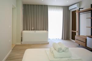 a bathroom with a tub and a bed with towels at ReiVal Hotel Marina Vlore in Vlorë