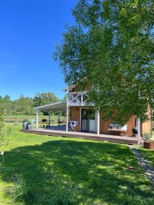 a house with a deck and a tree at Domek pod lasem „2” in Pasłęk