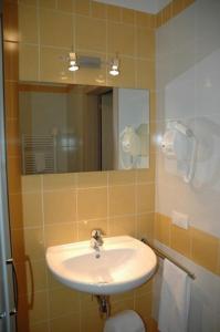 een badkamer met een wastafel, een spiegel en een toilet bij Hotel Fiera in Bolzano