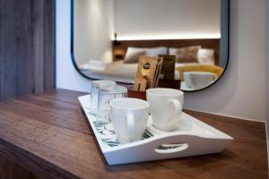 bandeja con tazas y vasos en una mesa con espejo en La Riva Luxury Rooms, en Rovinj