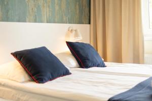 a bed with two black pillows on top of it at SeaSide Sopot - butikowe noclegi przy plaży in Sopot