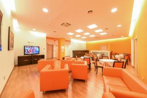 a restaurant with orange chairs and tables and a television at Hotel Fiera in Bolzano