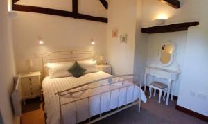 ein Schlafzimmer mit einem Bett, einem Tisch und einem Spiegel in der Unterkunft Hazel Cottage, Frithelstock in Frithelstock