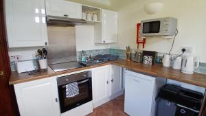 eine Küche mit weißen Schränken und einer Holzarbeitsplatte in der Unterkunft Hazel Cottage, Frithelstock in Frithelstock + 20 Fotos