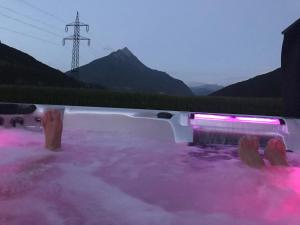 a person sitting in a hot tub with pink water at Apartment Comfort mit Fasssauna und Außen Whirlpool in Imsterberg