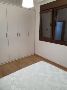 a bedroom with white cabinets and a bed and a mirror at Sol in Cangas de Morrazo