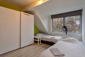 a small bedroom with two beds and a window at Duplex appartement in rustige woonwijk in Mortsel