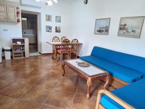 a living room with a blue couch and a table at Garden House KRISTI in Possidi
