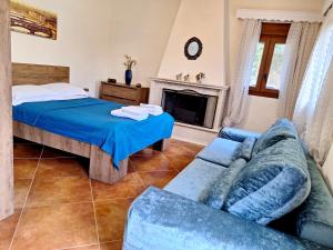 a bedroom with a bed and a couch and a fireplace at Garden House KRISTI in Possidi