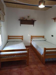 two twin beds in a room with white walls at Casita de Campo El Bujeo in Quéntar