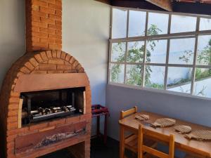 a room with a brick oven with a table and windows at Casa Maciel in São Thomé das Letras