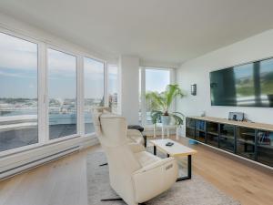 Una sala de estar con muebles blancos y grandes ventanales. en Inner Harbour Seascape - Views Views Views presented by Victoria Prime!, en Victoria