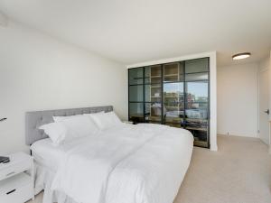 Un dormitorio blanco con una cama grande y una ventana. en Inner Harbour Seascape - Views Views Views presented by Victoria Prime!, en Victoria