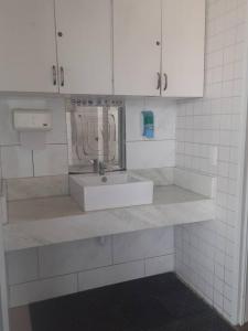 a white bathroom with a sink and a mirror at Golden Lake Apart Hotel , uma maravilha de lugar in Arraial do Cabo