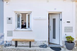 una panca di legno seduta di fronte a un edificio bianco di Casa Clara a Vila do Bispo Altre 21 foto