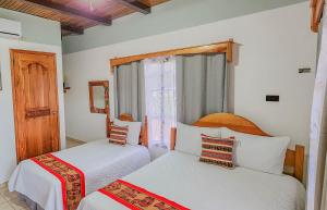 a bedroom with two beds and a window at Hotel Itzae in Copán Ruinas