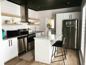 a kitchen with white cabinets and a black refrigerator at Downtown Campbellton Loft in Campbellton