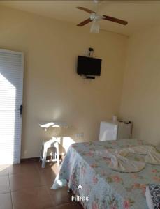 ein Schlafzimmer mit einem Bett und einem Fernseher an der Wand in der Unterkunft Hospedaria Coração de Pedra in São Thomé das Letras
