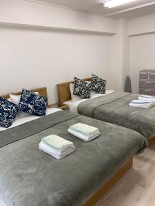 a room with two beds with folded towels on them at JR Shin-Osaka 30s, Direct to Kansai Airport 關西空港直達,Shinkansen to Tokyo, Tokyo & Nagoya, Universal Studio 16 mins, Umeda 6 mins, Kyoto 25 mins, Early Check-In in Osaka