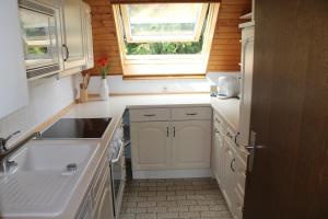 a kitchen with white cabinets and a sink and a window at Ferienwohnung Lodge am See - Terrasse - Kachelofen in ruhiger Lage nahe Schluchsee in Schluchsee +16 photos