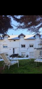 a large white building with two benches in front of it at Alojamiento Turístico Barrio Belgrano in San Carlos de Bariloche