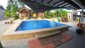 a swimming pool in a backyard with an umbrella at Laman Sakinah Merlimau in Merlimau