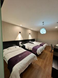 a hotel room with three beds and a blue light at 都市118酒店广电大厦店 in Qingdao +16 photos
