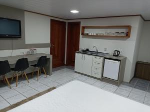a kitchen with a sink and a counter with chairs at Suite Familia A1 in Pomerode