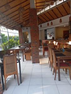 a restaurant with wooden tables and chairs and windows at Mansu Hotel and Spa Legian in Kuta