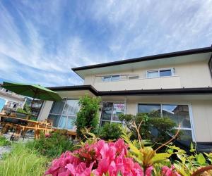 a house with a table and an umbrella and flowers at Moon River Court - Vacation STAY 19871v in Fujiyoshida