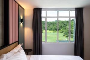 a bedroom with a window with a view of a green field at The Bayou Hotel Langkawi in Pantai Cenang