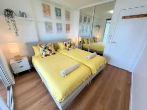 a bedroom with a large yellow bed with two pillows at Spacious Apt with pool & parking in Brisbane +8 photos