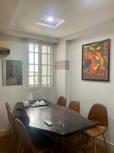 una mesa de comedor con sillas y una pintura en la pared en HOSTIE SAIGON [WANDERLUST Home], en Ho Chi Minh