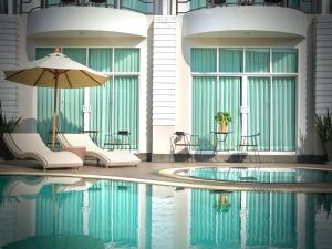 einem Pool mit Stühlen und einem Sonnenschirm neben einem Gebäude in der Unterkunft A-Te Chumphon Hotel - SHA Plus in Chumphon