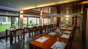 a restaurant with wooden tables and chairs and windows at Misty Grove Resort Hotel in Gūdalūr