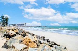 a beach with rocks and the ocean on a cloudy day at near beach unit 30 in Glenelg