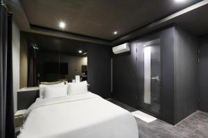 平泽市Pyeongtaek Moon Hotel的卧室里有一张白色的床和一面镜子