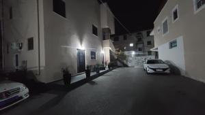 都拉斯Guest House Tian & Hojz的夜间停在大楼旁边的停车场