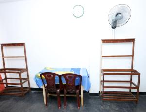 a table with two chairs and a fan next to it at Yarra BUNKZ Kandy in Kandy