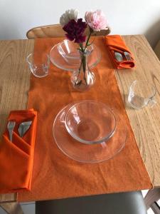 a wooden table with two plates and a vase of flowers at 2BR Podomoro Golf View Cimanggis with Netflix near exit Toll Jagorawi in Tjikuda Tiga