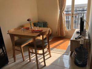 a living room with a table and chairs and a television at 2BR Podomoro Golf View Cimanggis with Netflix near exit Toll Jagorawi in Tjikuda Tiga